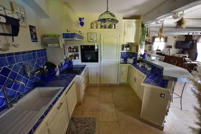 a large kitchen with blue tiled walls and counters at Villa le 62 Cazan in Vernègues