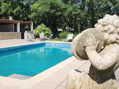 a statue sitting next to a swimming pool at Le Clos Renaissance in Oppède