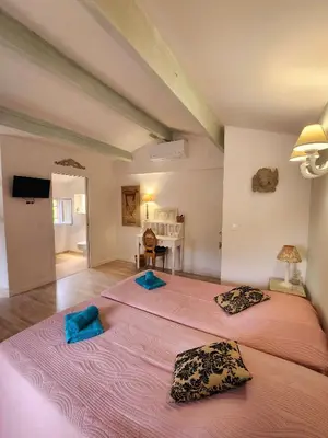 two beds in a room with two blue pillows at Le Clos Renaissance in Oppède