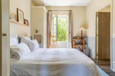 a large white bed in a room with a window at Les Deux Mas in Lagnes