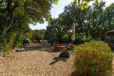 a backyard with a table and a umbrella and benches at Provencal bastide with heated pool near Alpilles and Luberon in Vernègues