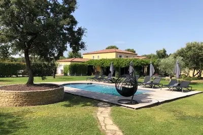 a swimming pool with chairs and a tree and a house at Villa Oasis Luxury and Relaxation in Provence in Lambesc