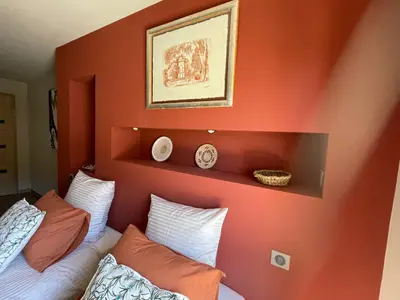 a bedroom with orange walls and a bed with pillows at KM2 in Bédoin