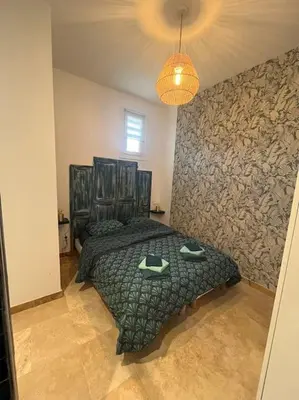 a bedroom with a bed with a green comforter at Le Platane Maison climatisée avec piscine in Monteux