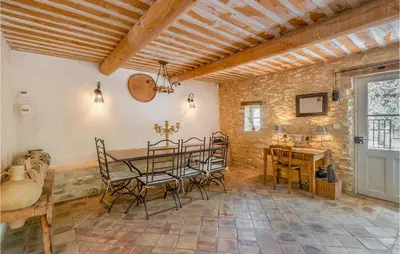 a dining room with a table and chairs and a stone wall at Belle Maison À Lacoste in Lacoste