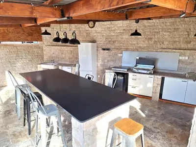 a kitchen with a large black table and chairs at Maison conviviale avec jardin proche Avignon + piscine partagée in Avignon