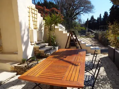 a wooden table sitting on the side of a building at Maison conviviale avec jardin proche Avignon + piscine partagée in Avignon