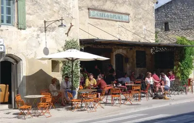 a group of people sitting at an outdoor cafe with an umbrella at Amazing Home In Saint Remy De Provence in Saint-Rémy-de-Provence