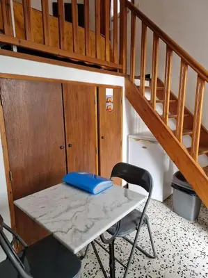 a table and a chair in a room with a staircase at Gîte Le Val des Fées classés deux étoiles in Roussillon