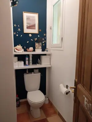 a bathroom with a toilet with shelves on the wall at La Maison du Chapelier in Fontaine-de-Vaucluse