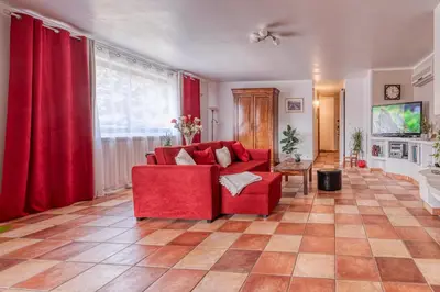 a living room with a red couch and red curtains at La Maison du Chapelier in Fontaine-de-Vaucluse