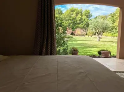 a bedroom with a large window with a view of a yard at Mas Libertino - Villa avec piscine & jacuzzi in Pernes-les-Fontaines
