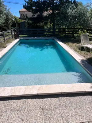 a swimming pool with blue water in a yard at LES VIEUX CABASSOLS VENELLES in Venelles