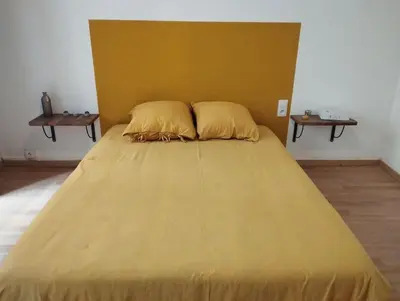 a large yellow bed with two pillows in a room at Appartement en plein centre. in Carpentras
