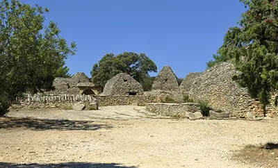 a group of stone buildings with trees in the background at Gordes Le Bastidon in Gordes