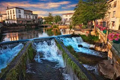 a river with waterfalls in a city with buildings at Maison de vacances Aubignan in Aubignan