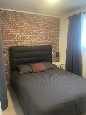 a bed in a bedroom with a brick wall at Appartement in Caumont-sur-Durance