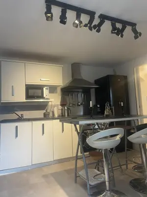 a kitchen with white cabinets and a counter with stools at Appartement in Caumont-sur-Durance