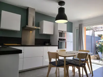 a kitchen with white cabinets and a table and chairs at Le temps d'une pause in Villes-sur-Auzon