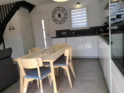 a table and chairs in a kitchen with a clock on the wall at Le temps d'une pause in Villes-sur-Auzon