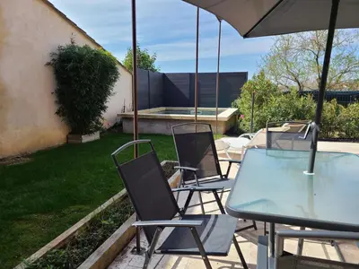 a table and chairs with a glass table and an umbrella at Le temps d'une pause in Villes-sur-Auzon