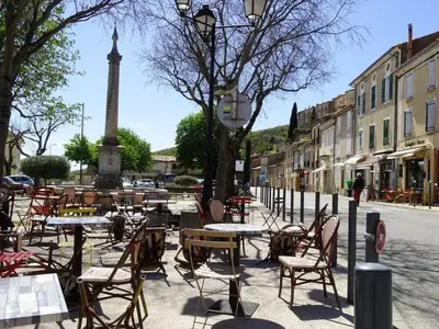 an empty street with tables and chairs and a monument at plein coeur de BANON in Banon