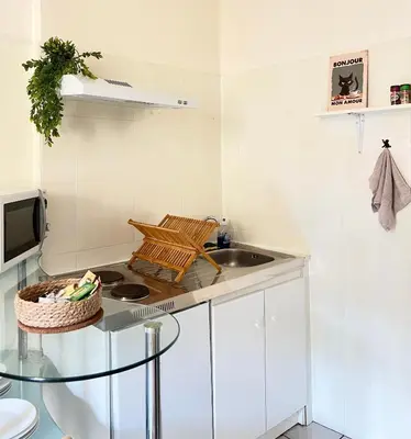 a living room with a glass table with a bottle of wine at Studio cœur de ville avec salle de bain privative & kitchenette in Carpentras