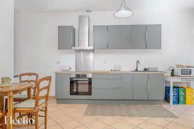 a kitchen with stainless steel appliances and a table and chairs at Maison Alena Lourmarin Main Square in Lourmarin