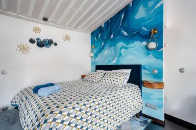 a bedroom with a bed and a painting on the wall at Aux Heures Bleues in LʼIsle-sur-la-Sorgue