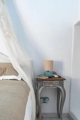 a bed with a table with a lamp on it at Aux Heures Bleues in LʼIsle-sur-la-Sorgue