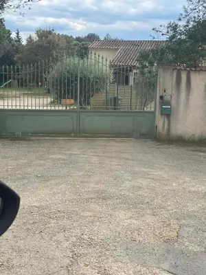a fence in front of a yard with a building at Appartement en campagne avec jardin et piscine in Grans