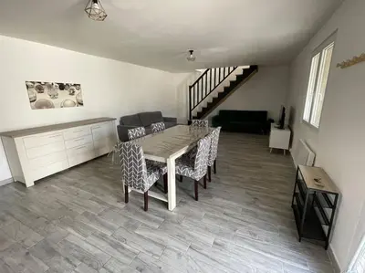 a dining room with a table and chairs and a staircase at Appartement en campagne avec jardin et piscine in Grans