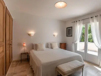 a white bedroom with a bed and a window at La Cadeline in Saumane-de-Vaucluse