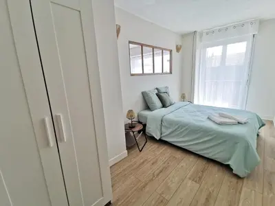 a white bedroom with a bed and a window at Appart'Cosy - clim - terrasse - ascenseur in Cavaillon