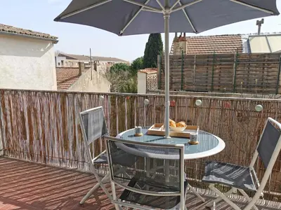 a table and chairs with an umbrella on a deck at Appart'Cosy - clim - terrasse - ascenseur in Cavaillon
