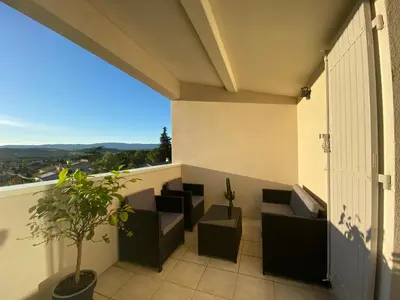 a balcony with couches and a potted plant at Beau Duplex climatisé T3 vue panoramique Luberon in Pertuis