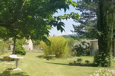 a garden with a table in the grass at Chambre dans Petit havre de paix avec piscine chauffée au coeur du Luberon in Gargas