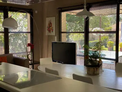 a living room with a table and a tv and windows at Maison AdriAnna in Vedène