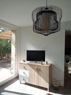 a living room with a television and a chandelier at Le charme de Landra in Pernes-les-Fontaines