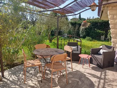 a patio with a table and chairs under a pergola at Le charme de Landra in Pernes-les-Fontaines