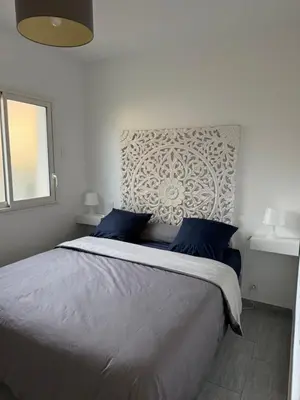 a bedroom with a large bed with blue pillows at Appartement cosy avec cour privée & terrasse Calme idéal couples familles in Cavaillon