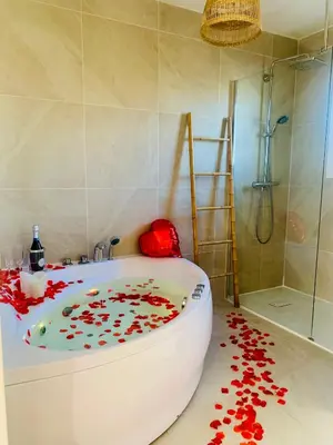 a bathroom with a bath tub with red petals on the floor at Provensa - love room avec balneo et terrasse avec vue in Pertuis