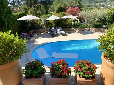 a swimming pool with chairs and umbrellas and flowers at la chamade grande chambre B&B indépendante in Ventabren