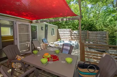a table and chairs on a deck with a red umbrella at Camping Le Luberon in Apt