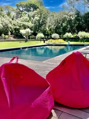 two pink umbrellas sitting next to a swimming pool at Domaine d'Hestia le gite Victoria in Rognes