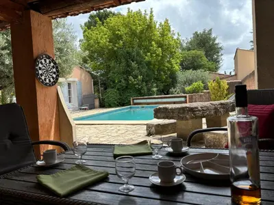 a wooden table with glasses and a bottle of wine at The Olive Garden - Charming Villa for 10 with pool and fast Wifi in Caromb