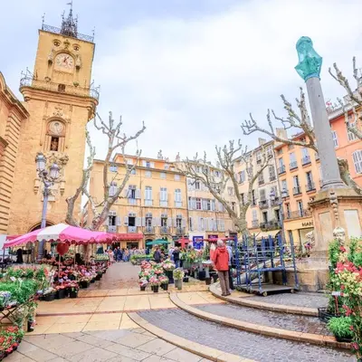 a city street with a clock tower and a market at Le Cosy Valcros, design et confort in Aix-en-Provence