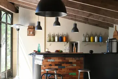 a kitchen with a bar with two stools and two lights at Profitez de la quiétude en bord de rivière, à 5 min du centre ville in LʼIsle-sur-la-Sorgue