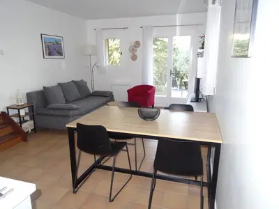 a living room with a wooden table and chairs at LES CISTES in Lioux