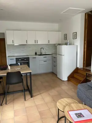a kitchen with white cabinets and a table and a refrigerator at LES CISTES in Lioux